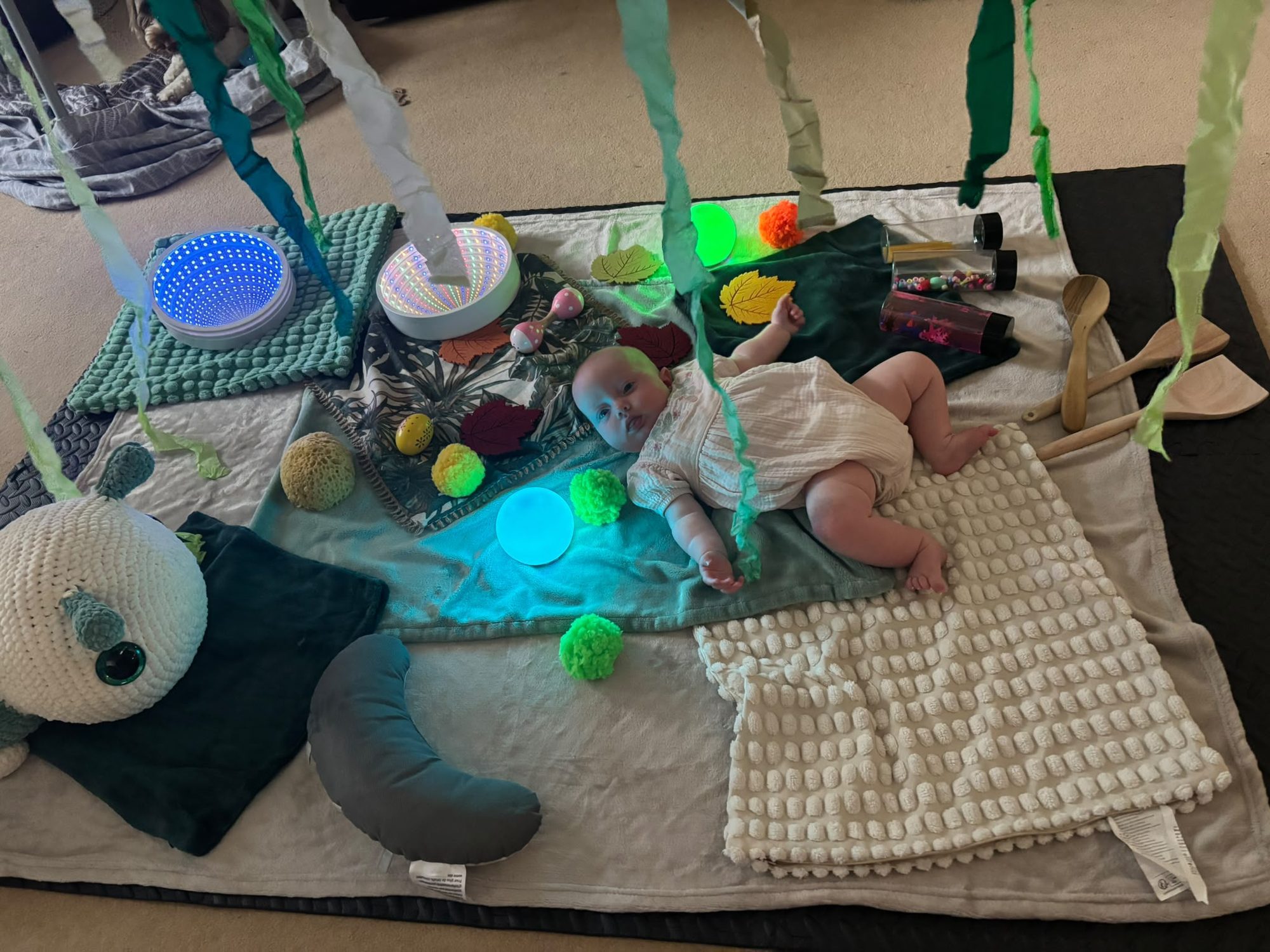 A full baby sensory setup with lights, ribbons, textured blankets and wooden toys
